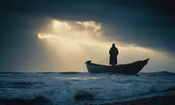 man on small boat in rough sea at sunset