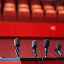 several microphones in front of red seats with no people