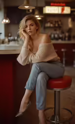 a girl is sitting on a red stool at a bar