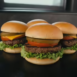 four hamburgers on a table sit together