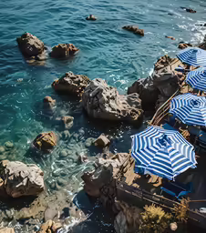 several umbrellas are set up on a rocky shore