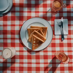 a plate with two pieces of food and a glass on the table