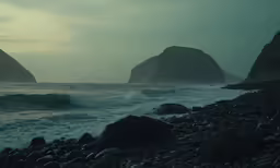 rocks and waves along the shore line in a dark landscape