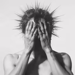 a shirtless person is covering his face and covering his ears
