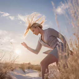 young woman in grey suit runs through the grass