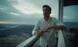 a man leaning on the railing looking at something