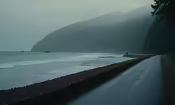 the road on which is very wet has water coming from its side and two boats near it