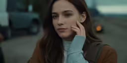 an attractive young woman in brown and blue sweater talking on cellphone