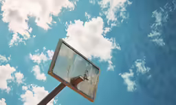 an old basketball hoop is shown against a partly cloudy sky