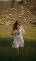 a woman with long red hair standing in tall grass