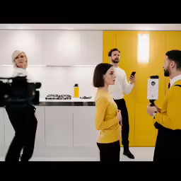 man and woman filming in modern yellow and white kitchen
