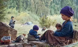 a girl sitting on the ground next to a couple of boys