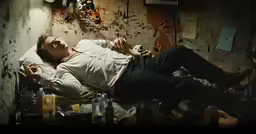 a man lying down on his stomach while wearing white shirt