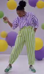 a girl in striped clothing juggles balls