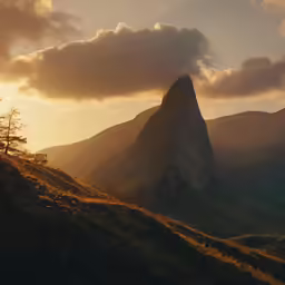 the sun rises behind a large mountain, surrounded by lush green hills