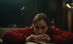 a woman wearing a red sweater and looking down at her hand