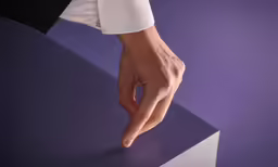 a person holding onto the edge of a small piece of furniture