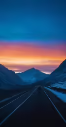 a street at night with mountains and an orange and pink sky