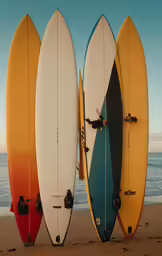 three surfboards stand tall on the sand beside the ocean
