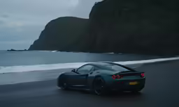 a silver sports car on the beach near a rocky cliff
