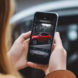 a person holding a cell phone in their hands with a red car on it