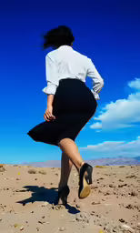 a woman in a skirt walking across sand