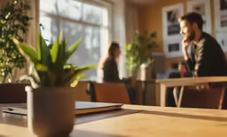 a man sitting in a chair at a table looking out the window
