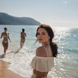 two women walking along a beach next to the ocean