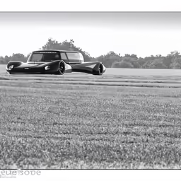 black and white photo of two cars, one on the ground