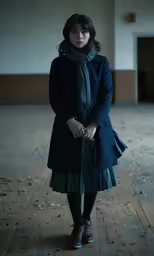 a woman standing in an empty room wearing a dark green dress