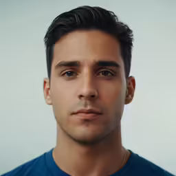 a man in a blue shirt looks into the camera
