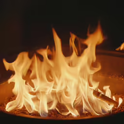 a pizza with flames in a pan over it