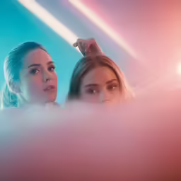 a close up of two girls standing together with bright lights