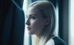 a woman with blonde hair looking out the window