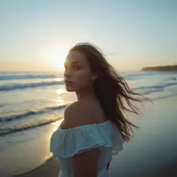 a girl standing on the beach at sunset