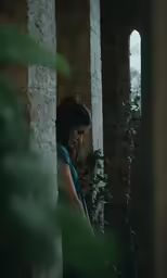 a woman standing next to a window with plants in it
