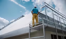 a man standing on a ladder above a metal roof