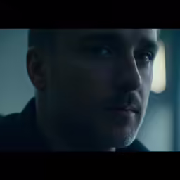 a man with grey hair and beard stares off into the distance