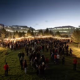 an event at night with people standing in the grass