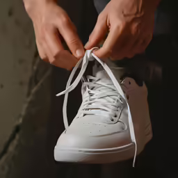 the man is tying up his tennis shoe