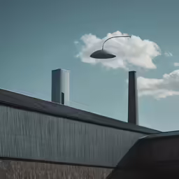 an industrial building with two chimneys next to a large cloud