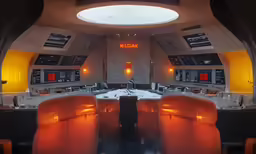 the view through an empty room of a conference set up with orange chairs