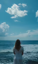 a woman standing on the beach looking at the ocean