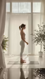woman in white yoga clothes standing in front of a window