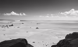 the beach with the rocks on the far shore has a body of water