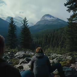 two people sit on rocks on the top of a mountain