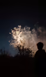 a man looks up at the night sky with stars as the firework is set off