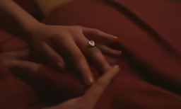 two people with one touching their fingers on a bed