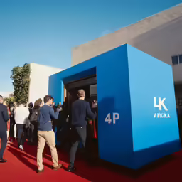 people getting out of the blue building on the red carpet