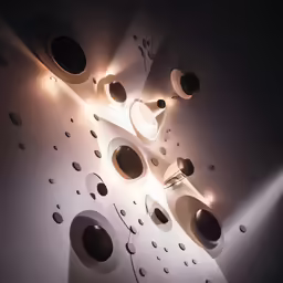 some lights and some black speakers on a white wall